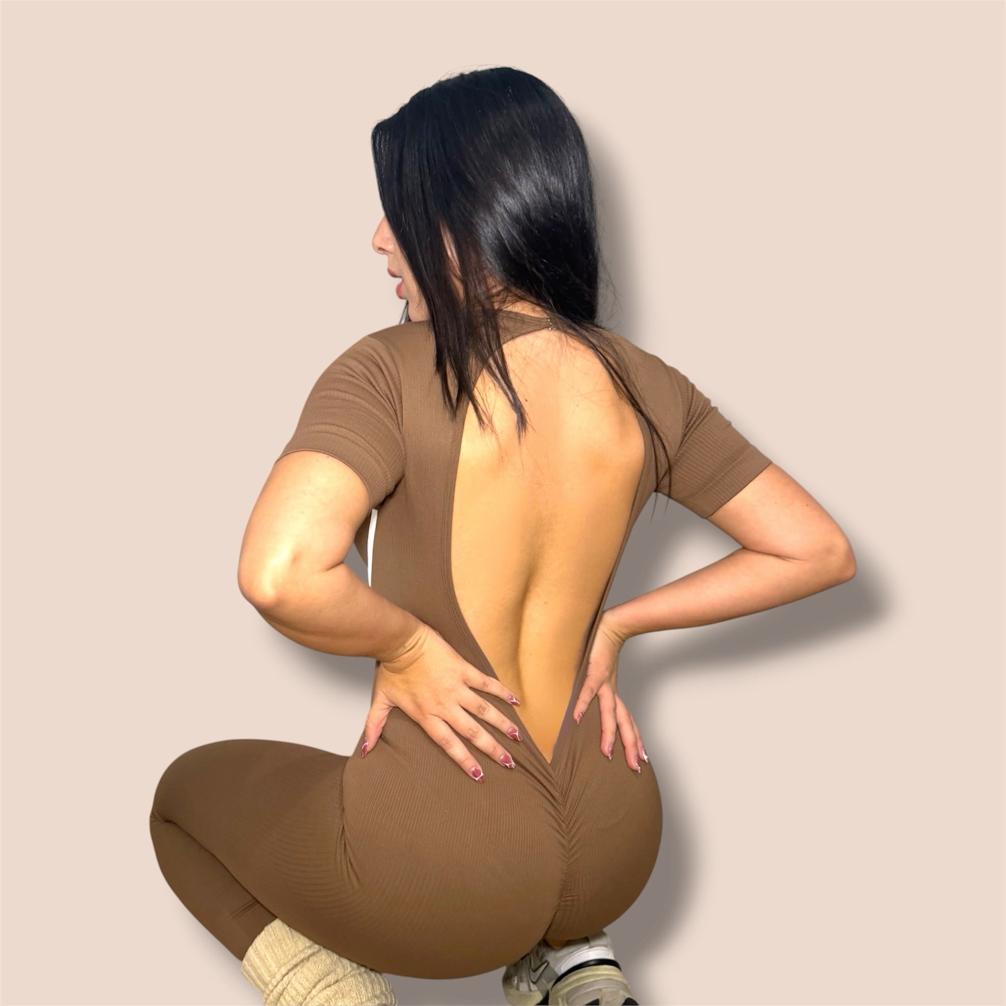 CASH SPORTWEAR brown ribbed short sleeve jumpsuit with open back and ruched detail on a model